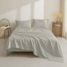 Neatly made bed with light gray bedding in a minimalistic bedroom.