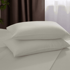 Two beige pillows on a bed with a blurred background
