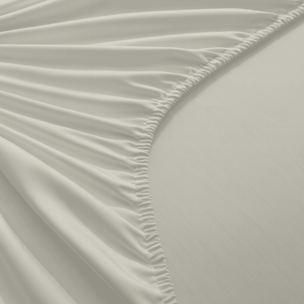 Close-up of light gray fitted sheet with ruffled edge on a bed.