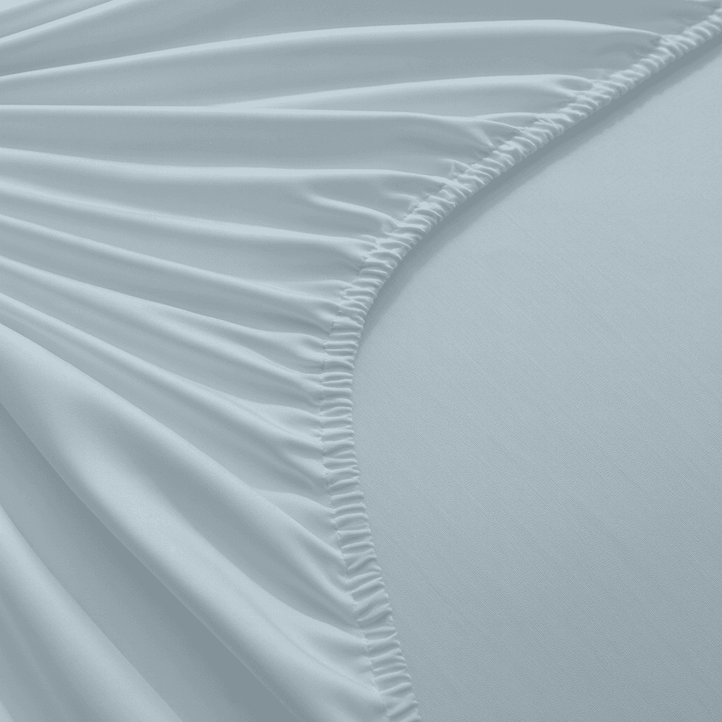 Close-up of light blue fitted sheet with subtle texture and folds.