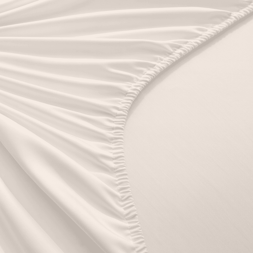 Close-up of white fitted sheet with subtle texture on a bed.