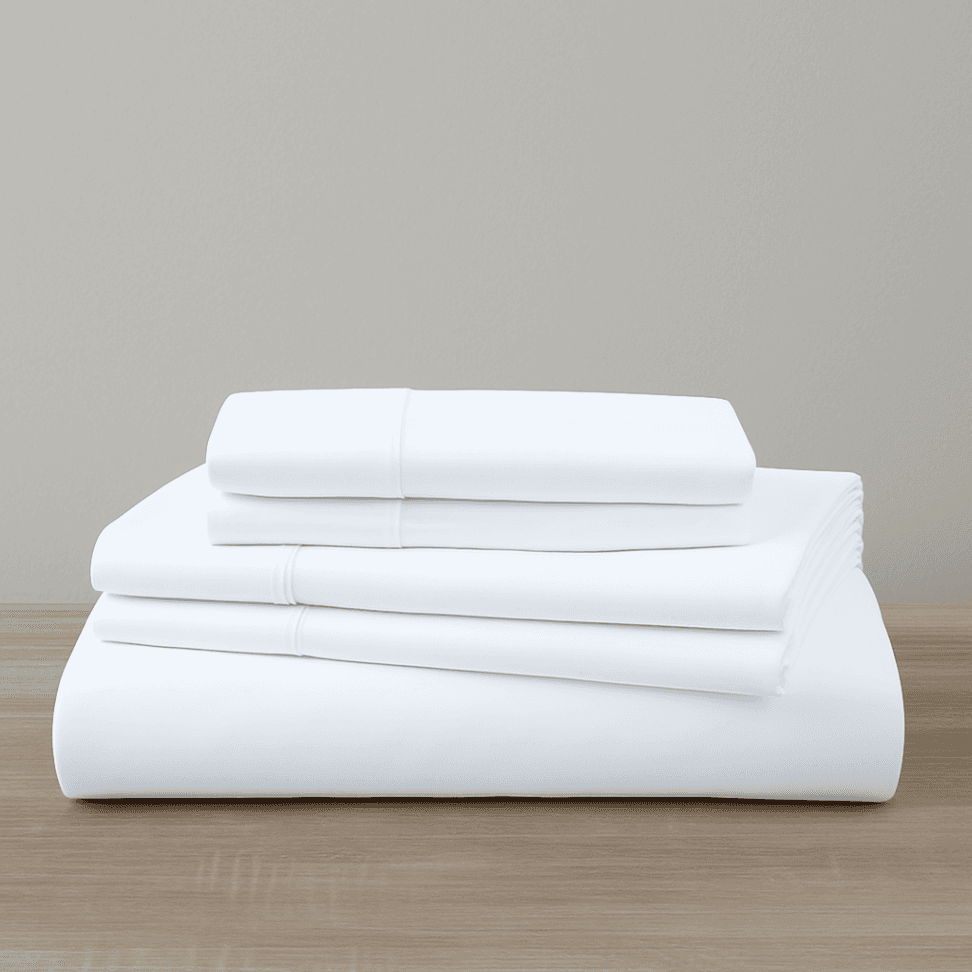 Stack of white folded Organic Cotton Sheet Set 500 Thread Count on a wooden surface with a neutral background