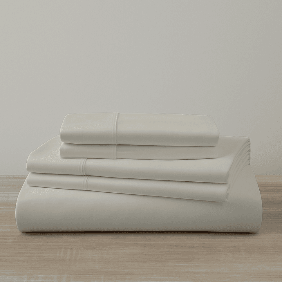 Beige bed sheets set on a wooden surface with a light gray background