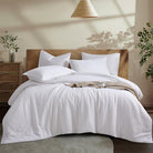 Neatly made bed with white Aurora Bloom Leaf Jacquard Duvet Cover Set White and pillows in a bedroom setting.