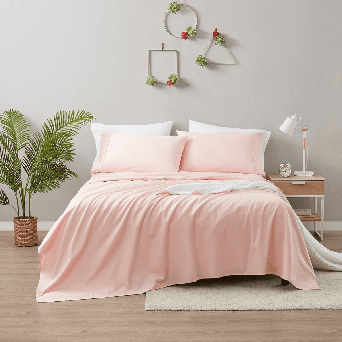 Bed with pink bedding in a bedroom setting with plants and decor.