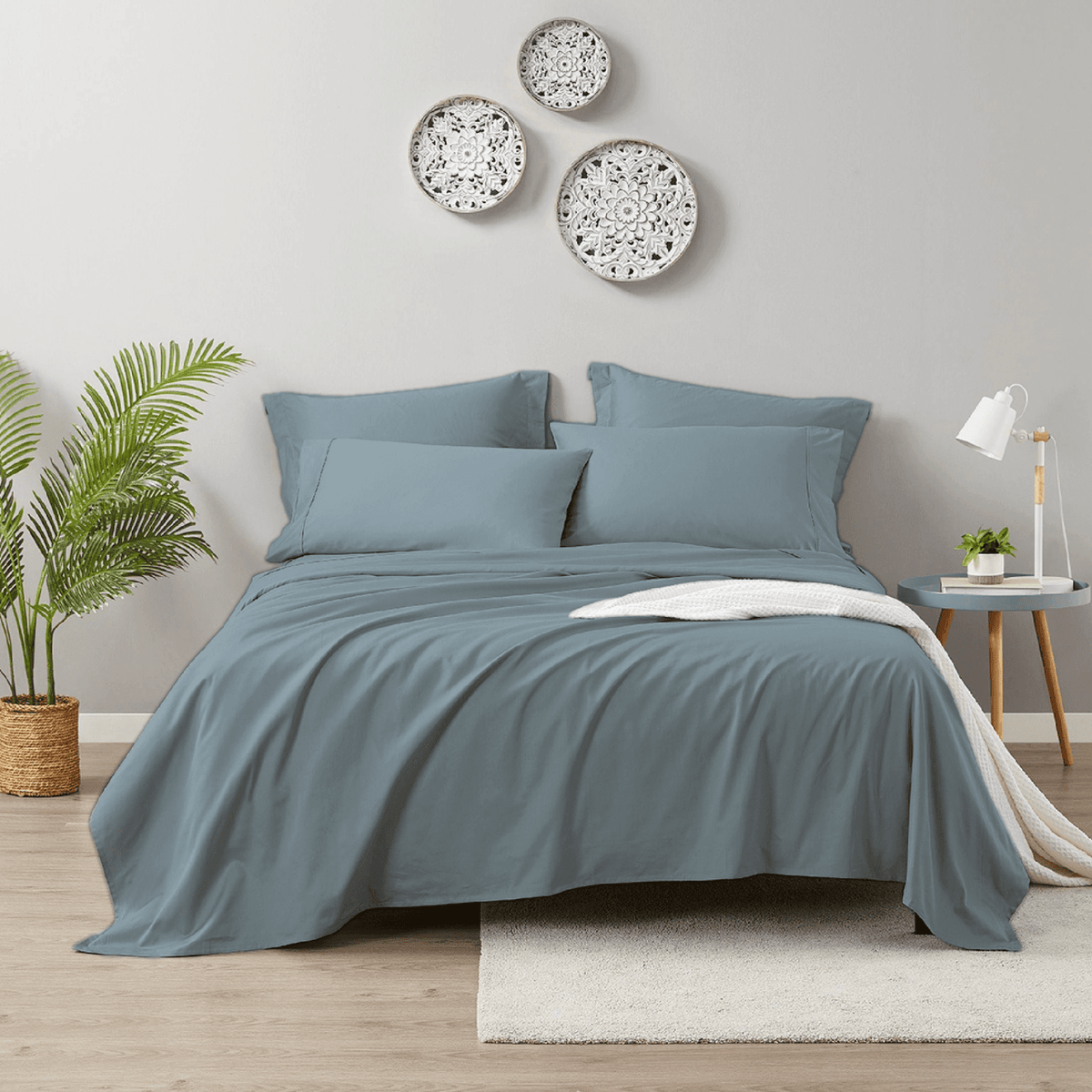 Blue bedding set on a bed in a bedroom with decorative plates on the wall.