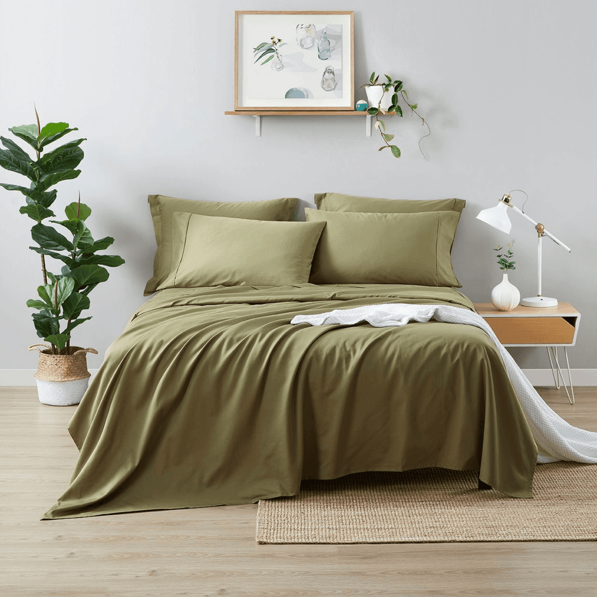 Green bedding set on a bed in a bedroom with plants and decor.