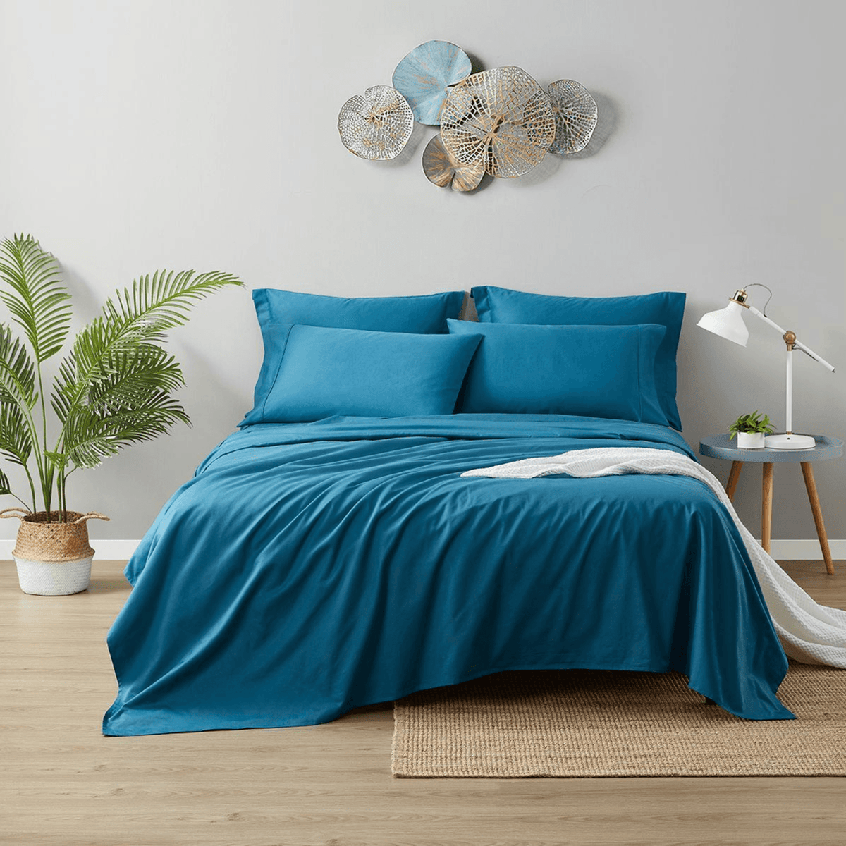 Blue bedding set on a bed in a bedroom with decorative elements.
