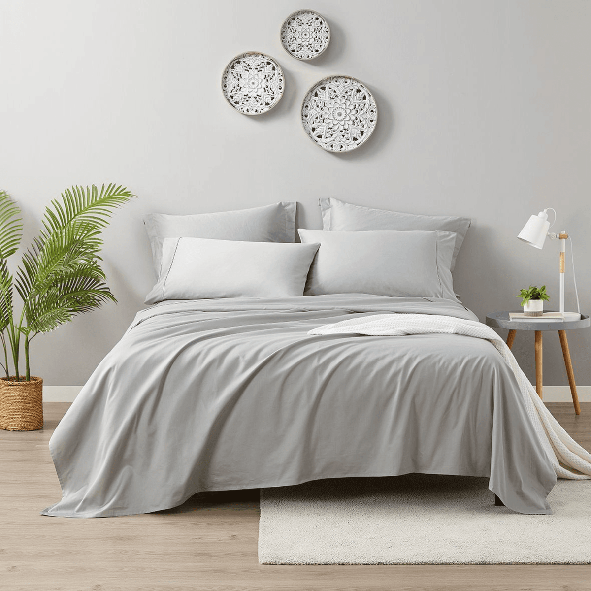Neatly made bed with gray bedding in a bedroom setting.