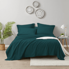 Teal bedding set on a bed in a bedroom with decorative plates on the wall.