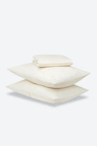 Stack of three white pillows on a light gray background
