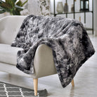 Gray patterned Hug Me Faux Weighted Throw Blanket draped over a beige sofa in a living room setting.