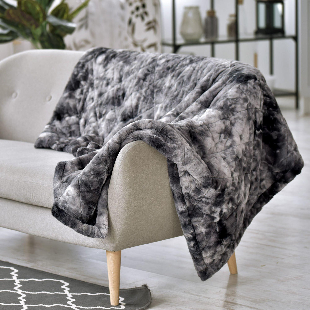 Gray patterned Hug Me Faux Weighted Throw Blanket draped over a beige sofa in a living room setting.