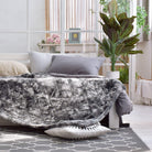 Hug Me Faux Weighted Throw Blanket on a bed in a bright bedroom with plants and decor.