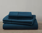 Set of blue bed sheets stacked on a wooden surface with a neutral background