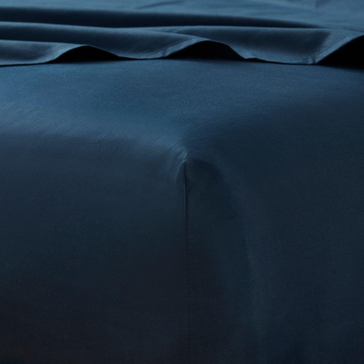 Dark blue bed sheets with a subtle texture on a plain background