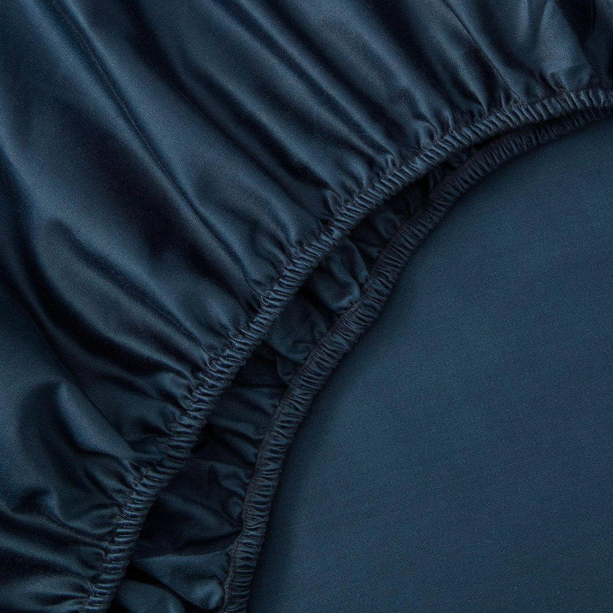 Close-up of a dark blue fitted sheet on a bed