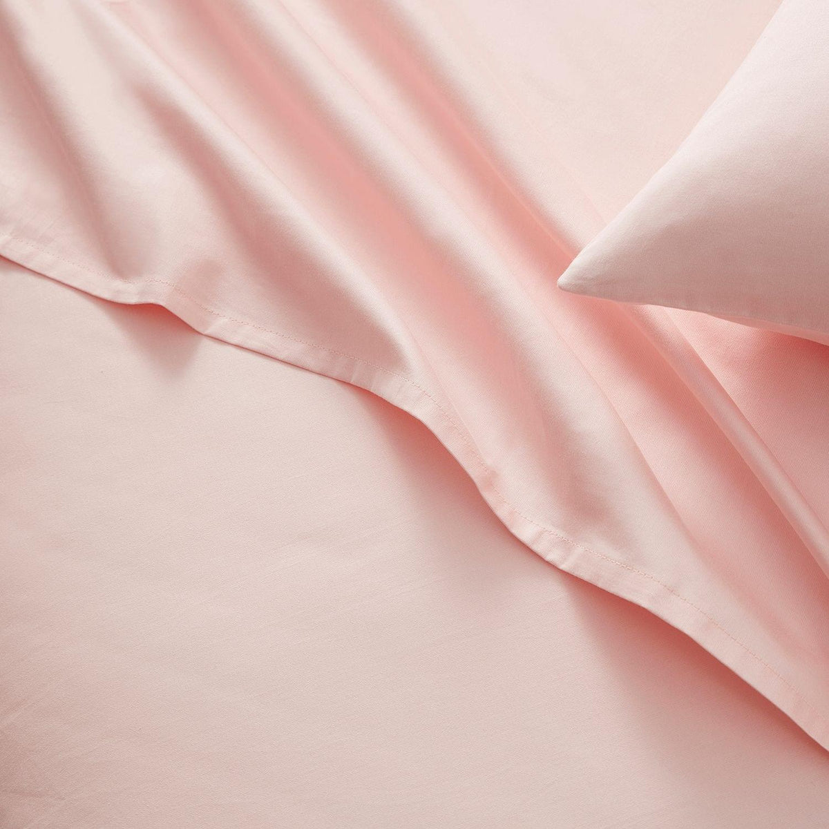 Close-up of pink satin fabric with a pillow.