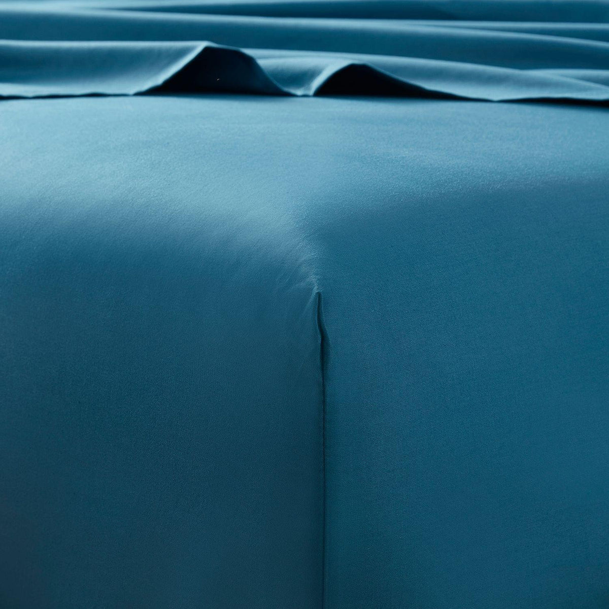Teal bed sheets with a subtle pattern on a plain background