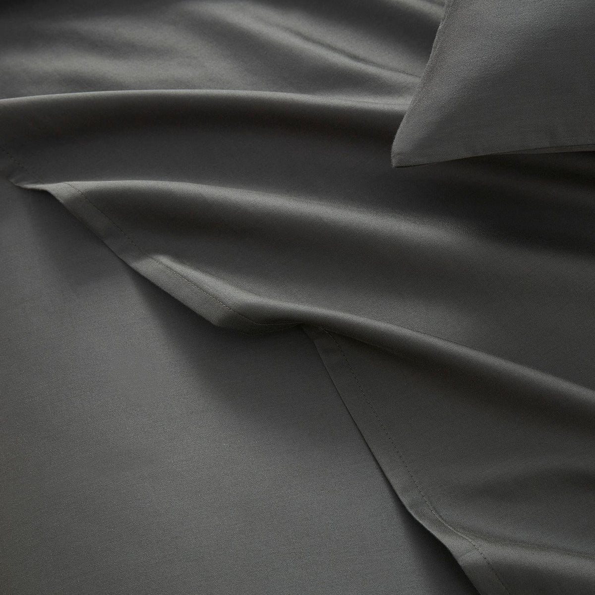 Dark gray bedding set with a pillow on a plain background