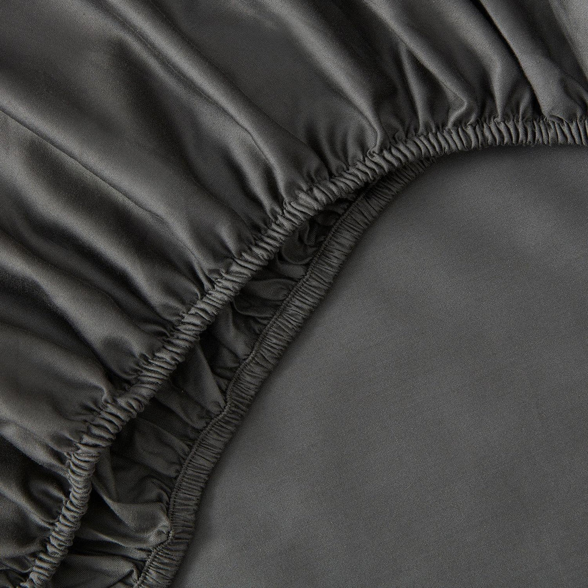 Close-up of a dark gray fitted sheet with elastic waistband
