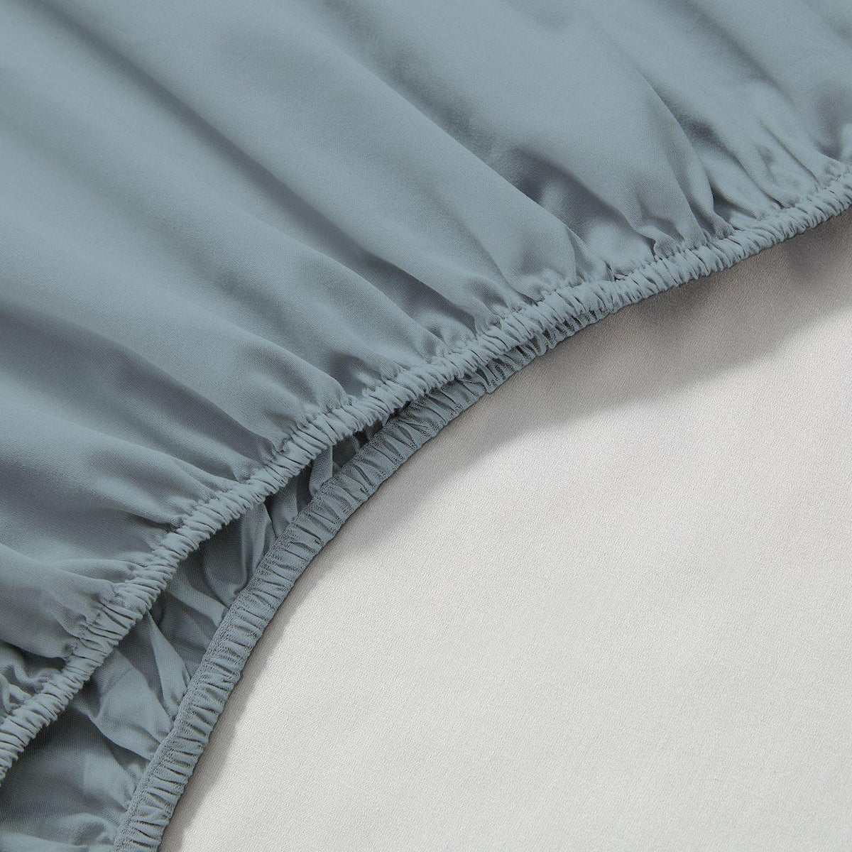 Close-up of a fitted sheet on a bed with a light background