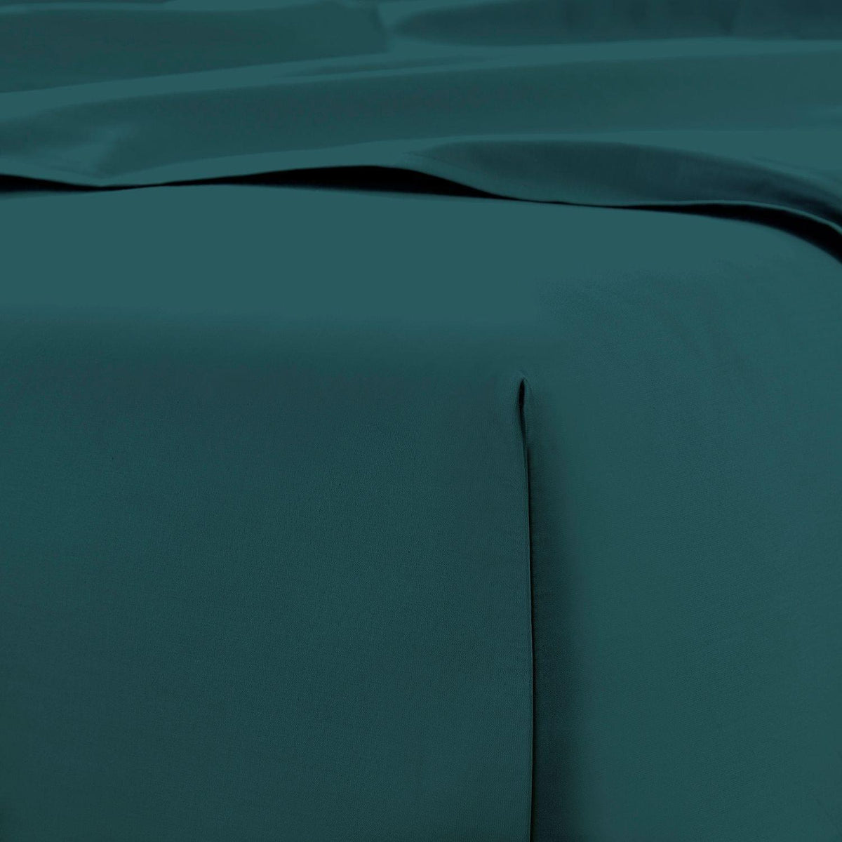 Teal bed sheets on a bed with a focus on texture and color.