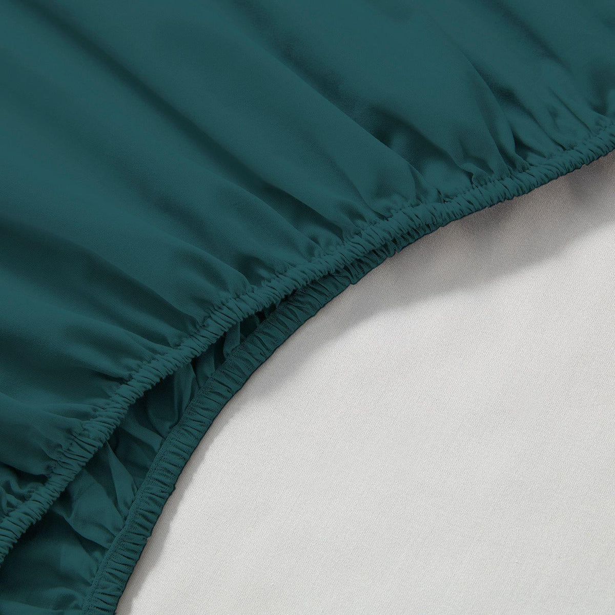 Teal fitted sheet on a bed with a white mattress