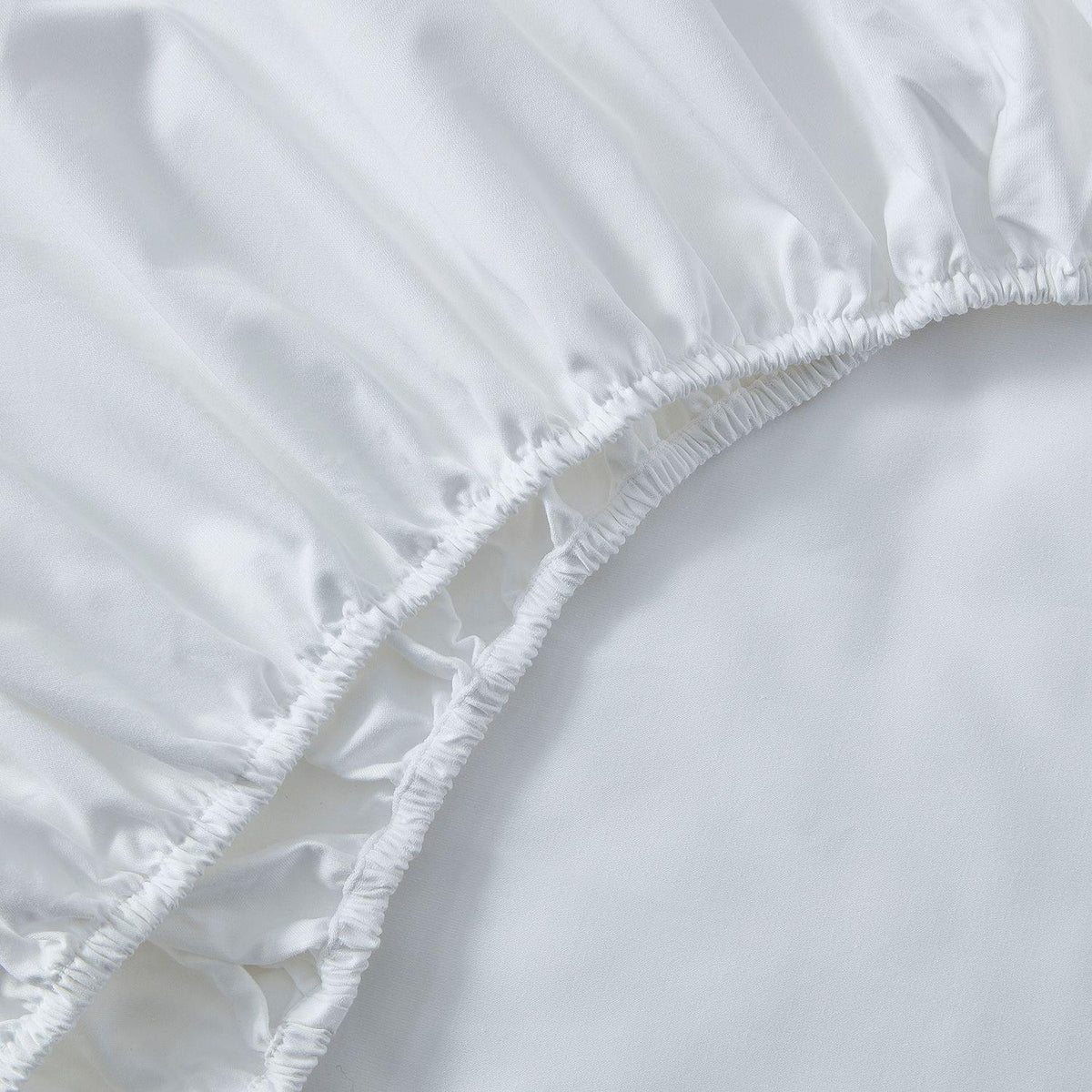 Close-up of a white fitted sheet with ruffled edge on a bed.
