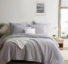 Gray checkered Seersucker Euro Sham set on a bed in a bright bedroom with a plant and framed picture.
